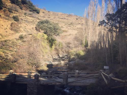 a bridge over a stream in a mountain at Apartamentos Vista Veleta in Capileira