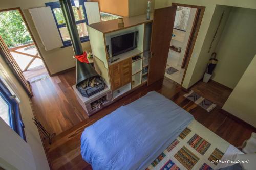 een woonkamer met een bed en een televisie bij Pousada Ribeirao da Floresta in Lumiar