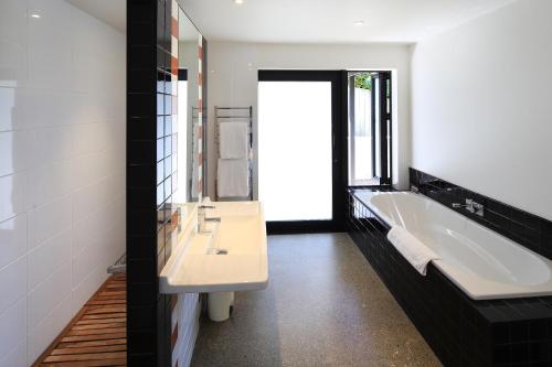 a bathroom with a white tub and a sink and a bath tub at Blackwood Retreat in Oneroa