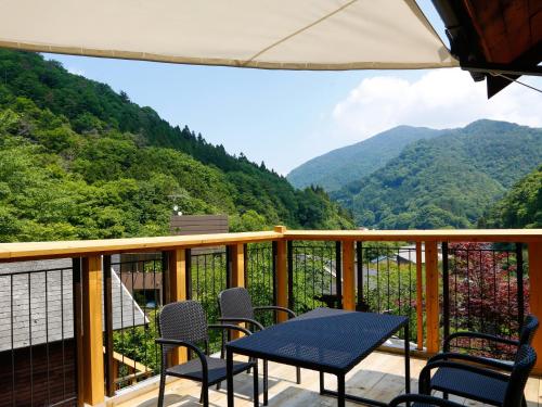a balcony with a table and chairs and mountains at Asan Kotonami in Manno