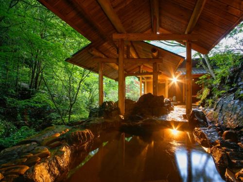 a wooden cabin with a pond in front of it at Asan Kotonami in Manno