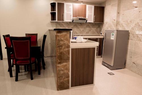 a kitchen with a counter with chairs and a refrigerator at Rolana Furnished Apartments in Jeddah