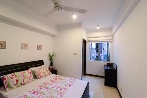 a bedroom with a bed with pink pillows and a window at On 320 Apartment in Colombo