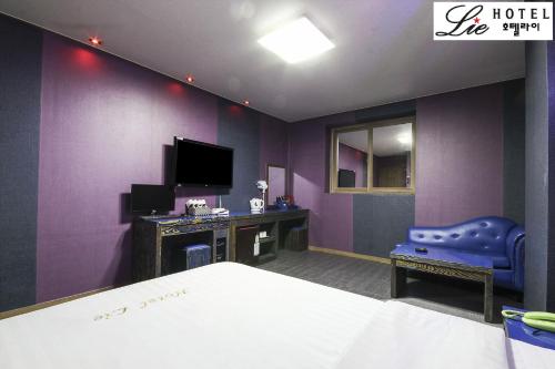 a bedroom with purple walls and a bed and a tv at Hotel Lie in Geoje 