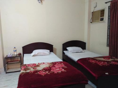 a bedroom with two beds with red sheets and a table at Hotel Plaza in Bāndarban