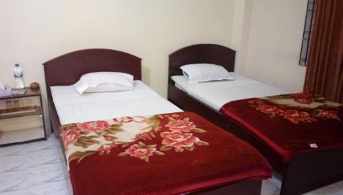 two beds in a hotel room with red blankets at Hotel Plaza in Bāndarban