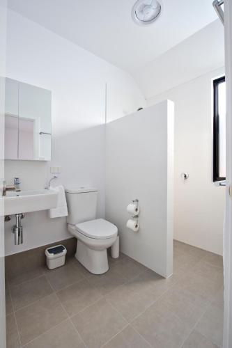 a white bathroom with a toilet and a sink at Margaret River Bungalow-1-street - pet friendly in Margaret River Town