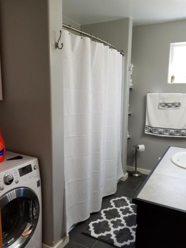 a laundry room with a washer and a white shower curtain at Rustic Elegance in Talkeetna