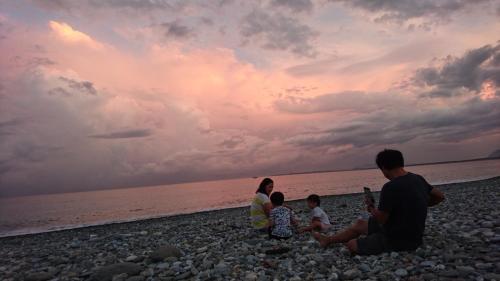 a family sitting on the beach watching the sunset at Flower and Green Collection in Shunan