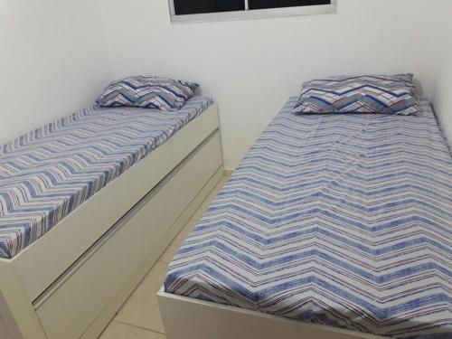 dos camas sentadas una al lado de la otra en un dormitorio en Condominio Mar de Gales en Macaé