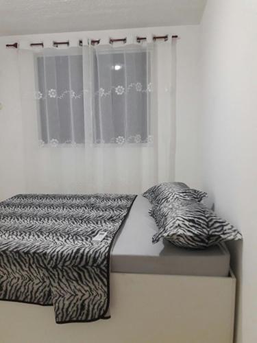 a bed in a bedroom with a zebra blanket and a window at Condominio Mar de Gales in Macaé