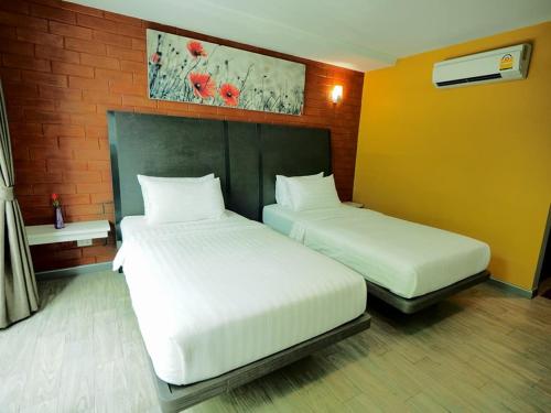 two white beds in a room with a brick wall at BB House Khlongtan in Bangkok