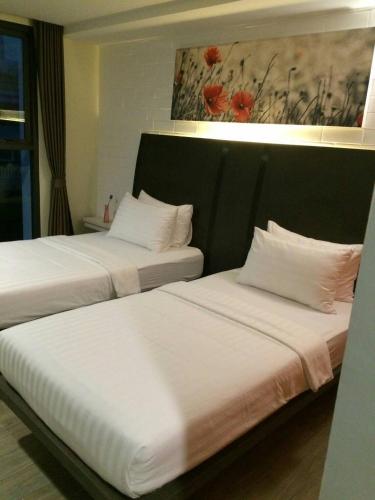 two beds with white pillows in a hotel room at BB House Khlongtan in Bangkok