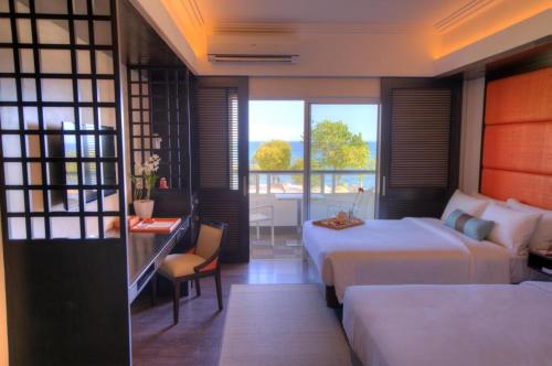 a hotel room with two beds and a table with a desk at BE Grand Resort, Bohol in Panglao