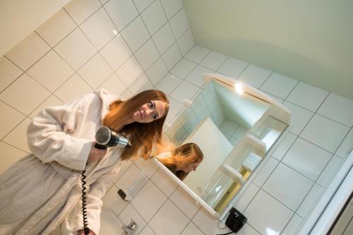 Una donna che si spazzola i capelli nello specchio del bagno di Pension Central a Markt Piesting