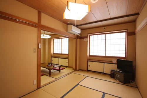 Cette chambre vide dispose d'une télévision et de deux fenêtres. dans l'établissement Kawahiro, à Nozawa Onsen