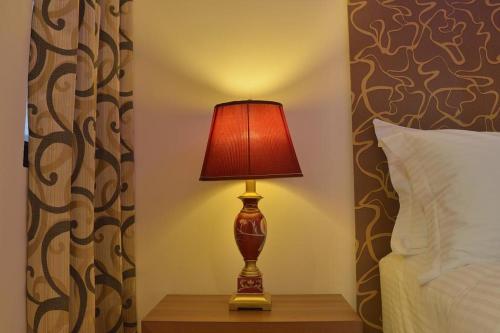 a lamp on a table next to a bed at Turquoise Residence by UI in Hulhumale