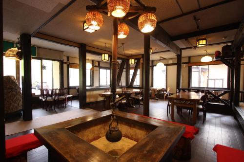 un restaurante con mesas, sillas, luces y ventanas en Kawahiro, en Nozawa Onsen