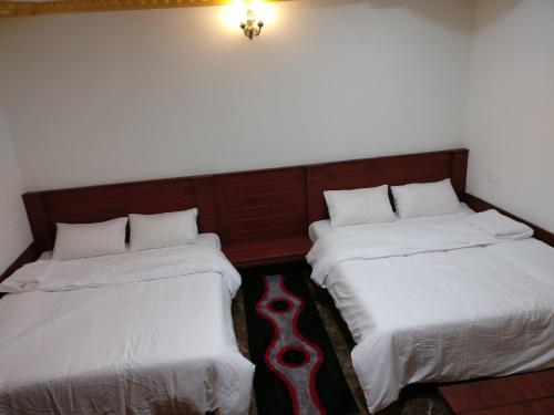 two beds sitting next to each other in a room at The Shades Holiday inn in Kushālnagar