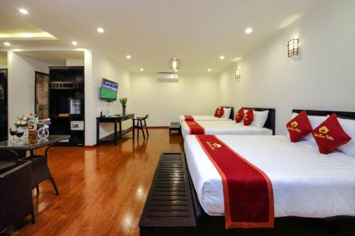 a hotel room with two beds and a television at Little Town Villa in Hoi An