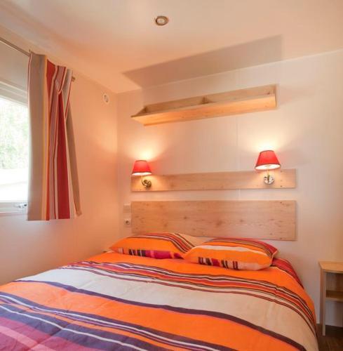 - une chambre avec un lit et deux oreillers orange dans l'établissement Les Roulottes de Cuzay, à Roiffé