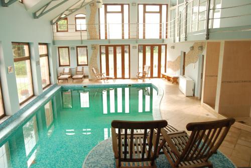a large swimming pool with two chairs in a building at Hotel Villa Majur in Subotica