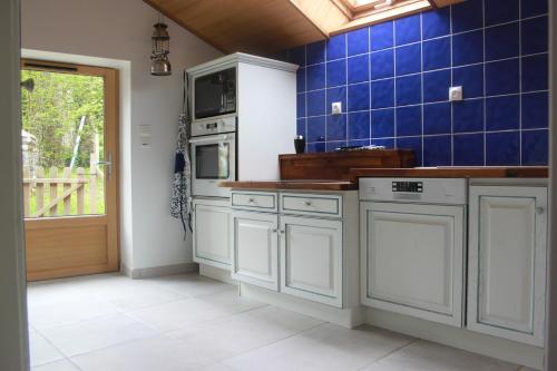 Il comprend une cuisine avec des placards blancs et un mur carrelé bleu. dans l'établissement les gites du grenit, à La Chapelle-Neuve