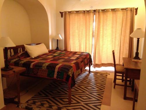 a bedroom with a bed and a desk and a window at Neemrana's - Tijara Fort Palace in Alwar