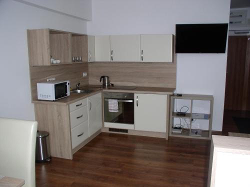 a kitchen with white cabinets and a sink and a microwave at Apartmán Cyril A 104 in Smokovce