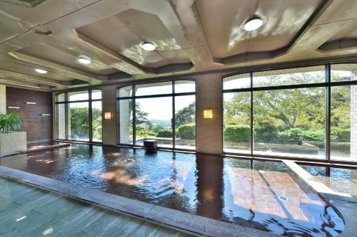 an indoor swimming pool with a large room with windows at Shizuoka Country Hamaoka Course & Hotel in Omaezaki