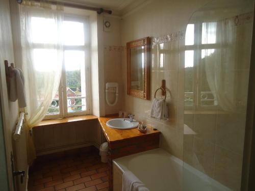 ein Badezimmer mit Badewanne und Waschbecken und einem Fenster in der Unterkunft Hôtel De La Barbacane in Tiffauges