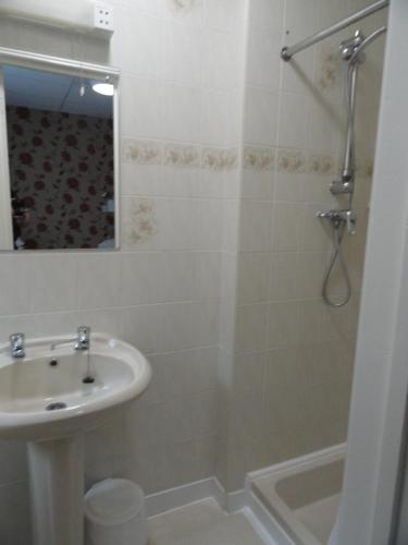 a white bathroom with a sink and a shower at The Beechfield Hotel in Blackpool