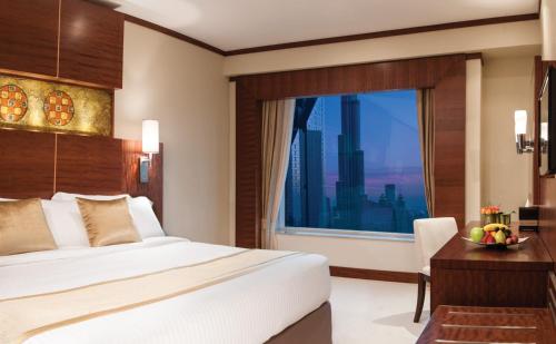 a bedroom with a large bed and a large window at Carlton Downtown Hotel in Dubai