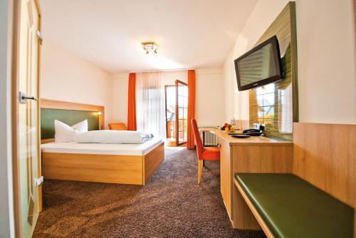 1 dormitorio con 1 cama y escritorio con TV en Danner´s Hotel Löwen, en Marschalkenzimmern