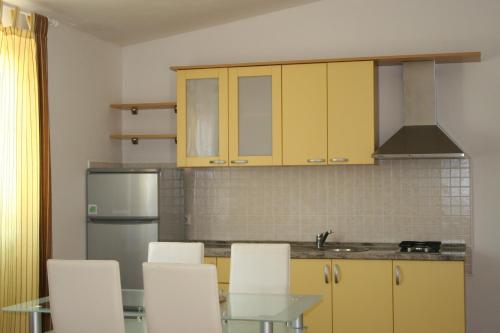 cocina con mesa de cristal y sillas blancas en Apartments Sara en Vlašići