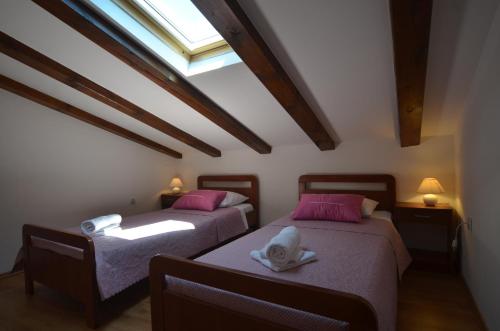 Dos camas con almohadas rosas en una habitación con ventana. en Apartment Casa Nova, en Rovinj