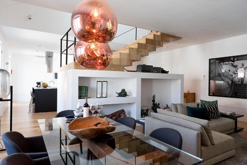 een woonkamer met een glazen tafel en een trap bij Flora Chiado Apartments in Lissabon