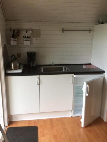 a kitchen with white cabinets and a sink at Bredebro camping in Bredebro