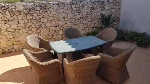 una mesa con sillas de mimbre alrededor con una pared de piedra en Vishnji Vege Gajac, en Novalja