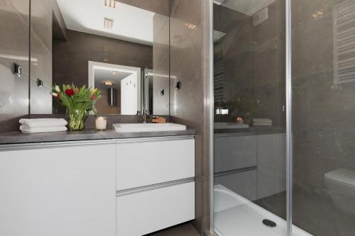 a bathroom with a glass shower and a sink at Jantar Apartamenty Design Latarnia Morska in Kołobrzeg