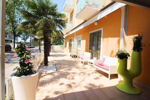 patio z krzesłami i palmami obok budynku w obiekcie Hotel Eraclea w mieście Lido di Jesolo