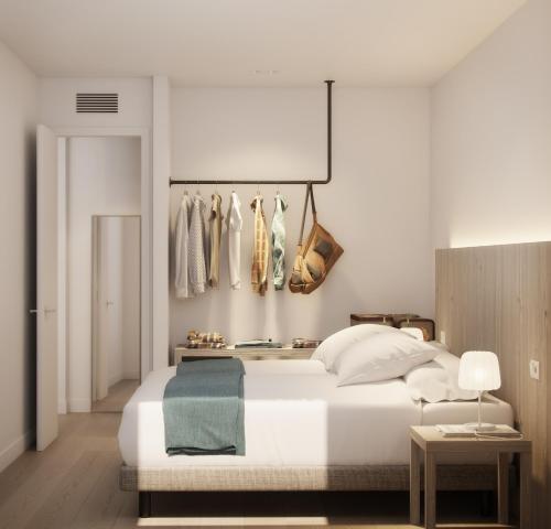sypialnia z białym łóżkiem i wieszakiem na ubrania w obiekcie Sunrise Suites w mieście Ibiza