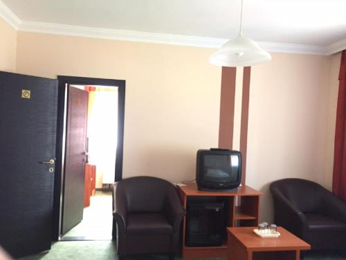 a living room with two chairs and a tv at Europa Hotel És Étterem in Nyíregyháza