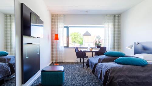 a room with two beds and a table with a television at Glostrup Park Hotel in Glostrup