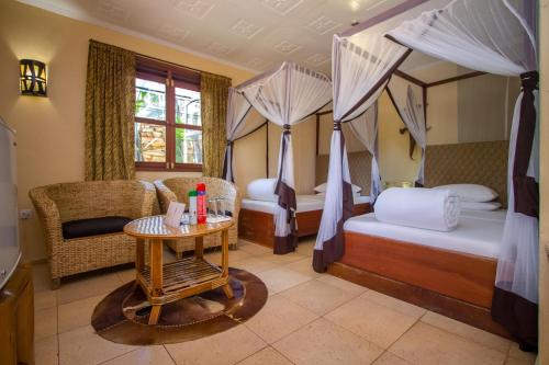 a bedroom with two beds and a table and chairs at 2 Friends Guest House in Jinja