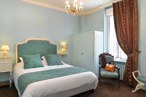 um quarto com uma cama, uma cadeira e um lustre em Logis Hôtels Restaurant Le Dauphin em Salbris