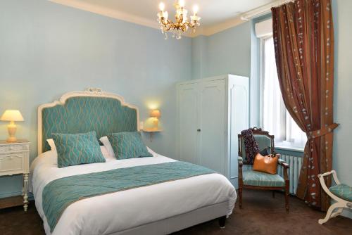 a bedroom with a bed and a chair and a chandelier at Logis Hôtels Restaurant Le Dauphin in Salbris