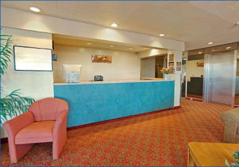 a lobby with a blue counter and a pink chair at Travelodge by Wyndham Cleveland Airport in Brook Park