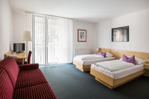 バート・タッツマンスドルフにあるKaplan am Kurparkのベッド2台とソファが備わるホテルルームです。