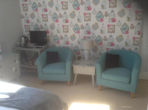 a bedroom with two chairs and a desk with a computer at The Lychgate in Caldicot